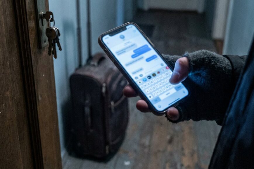 Illustration : un voyageur écrit à l’assistance Airbnb depuis son téléphone, devant la porte d’un logement dont les clés sont restées dans la serrure